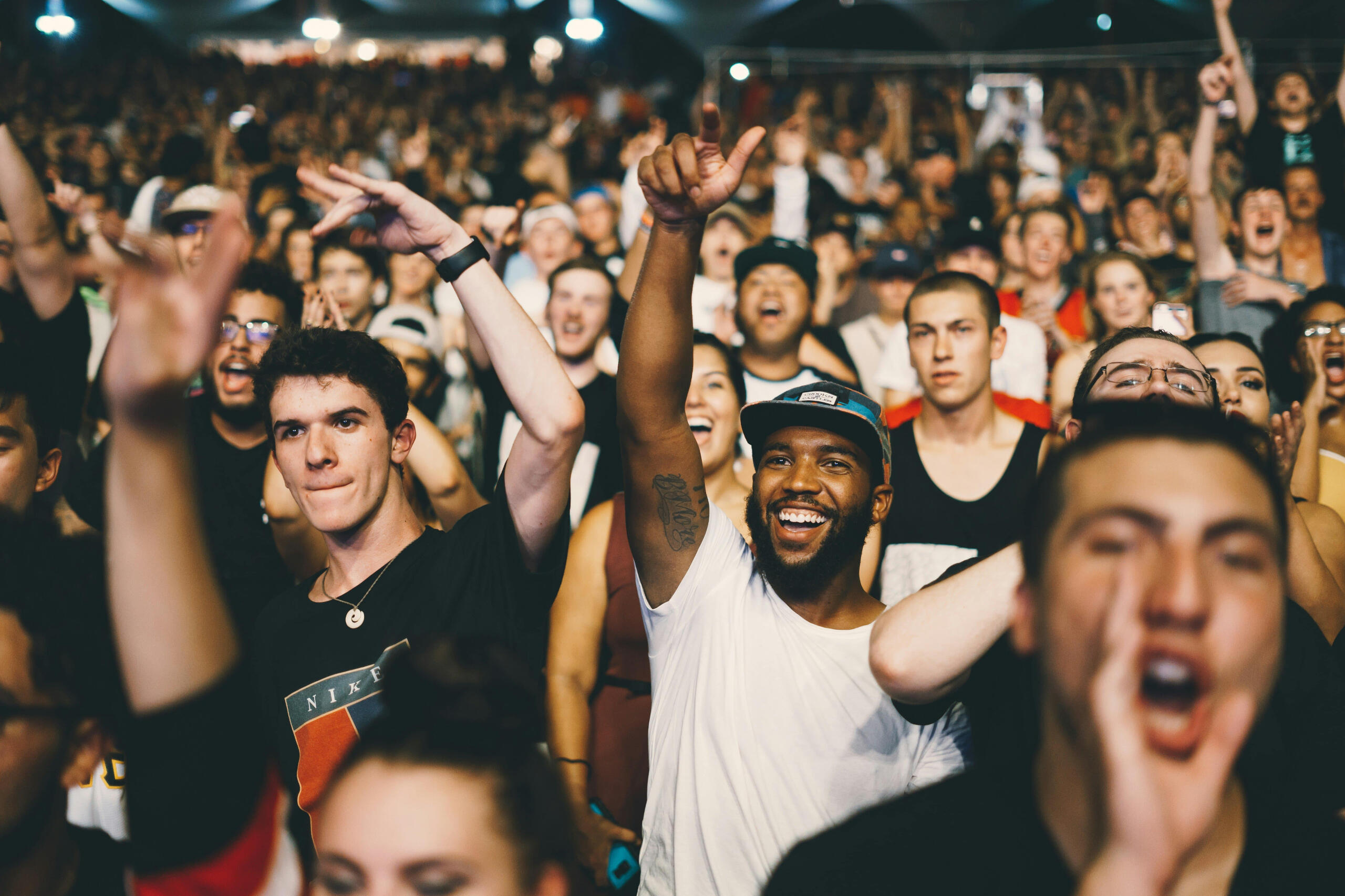 A crowd of people singing & dancing at a concert.